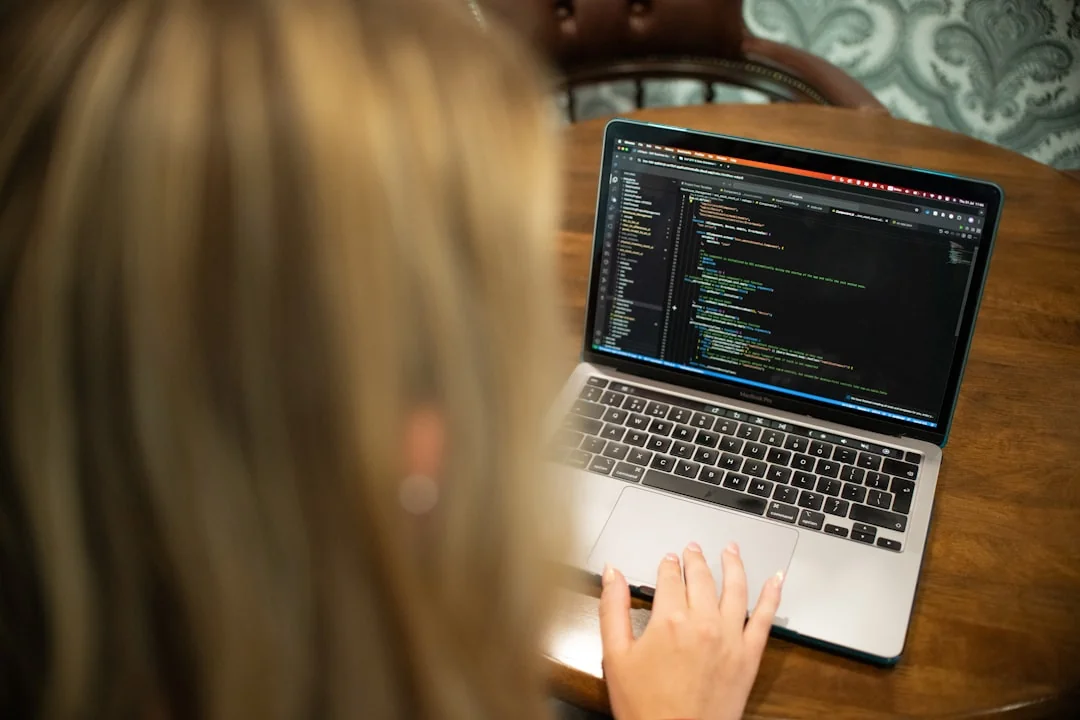 A photographer working at a creative setup with a laptop and Wacom tablet, focused on editing photos indoors.